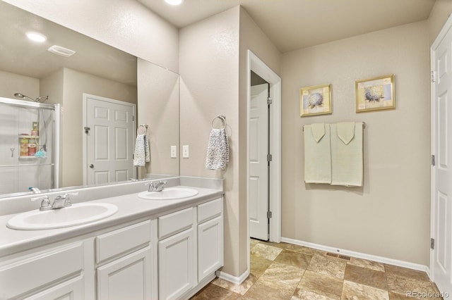 full bath featuring a sink, baseboards, double vanity, and a shower stall