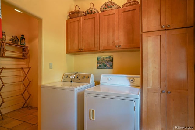 clothes washing area with cabinets, tile patterned floors, and washer and dryer