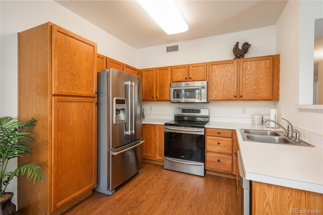8775 W Berry Ave Unit 101, Littleton, CO 80123 - kitchen with stainless steel appliances, light countertops, wood finished floors, visible vents, and a sink