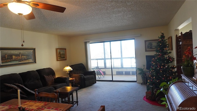 carpeted living room featuring ceiling fan and a textured ceiling