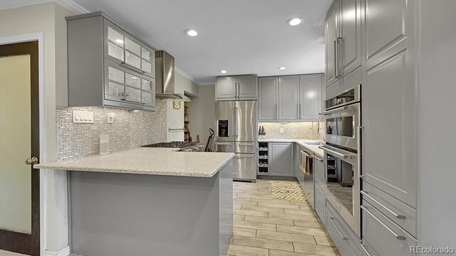 12020 W Alabama Pl, Lakewood, CO 80228 - kitchen featuring gray cabinets, appliances with stainless steel finishes, wall chimney range hood, crown molding, and a peninsula
