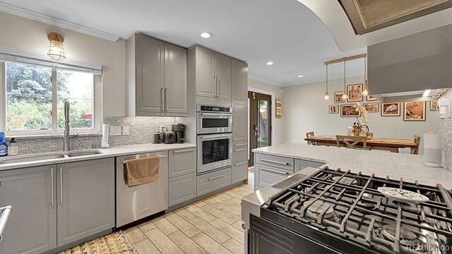 12020 W Alabama Pl, Lakewood, CO 80228 - kitchen with gray cabinetry, appliances with stainless steel finishes, tasteful backsplash, light wood-style floors, and ornamental molding