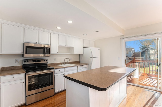 kitchen featuring white cabinets, sink, a kitchen island, and stainless steel appliances