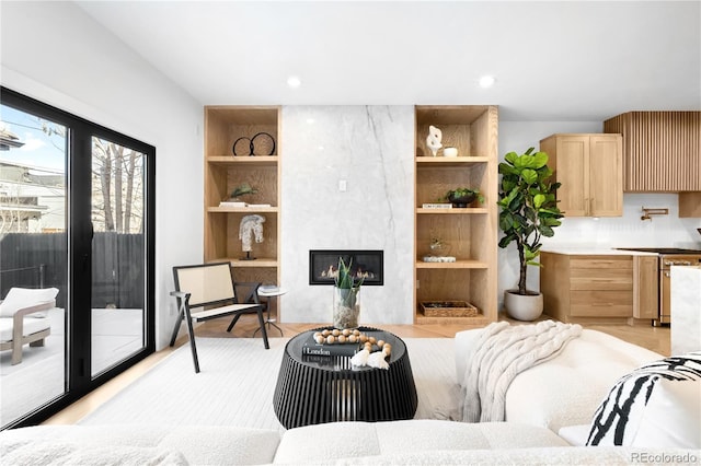 living area with recessed lighting, built in shelves, a fireplace, and light wood-type flooring