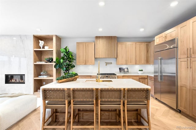 kitchen with stainless steel built in refrigerator, recessed lighting, a fireplace, and light brown cabinetry