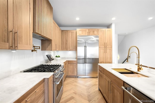 kitchen with range hood, recessed lighting, a sink, light countertops, and high quality appliances