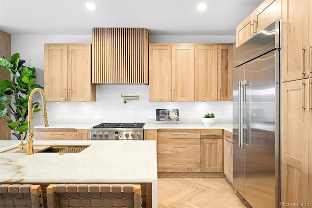 kitchen with stove, light brown cabinets, extractor fan, and built in fridge