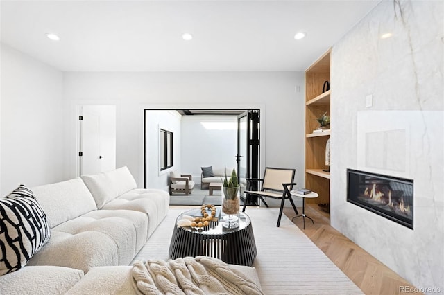 living area with recessed lighting, light wood-type flooring, built in features, and a fireplace