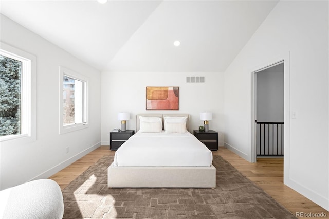 bedroom featuring visible vents, wood finished floors, baseboards, and vaulted ceiling