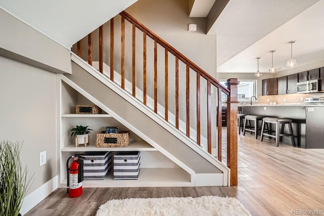 staircase with a high ceiling, sink, hardwood / wood-style floors, and built in features