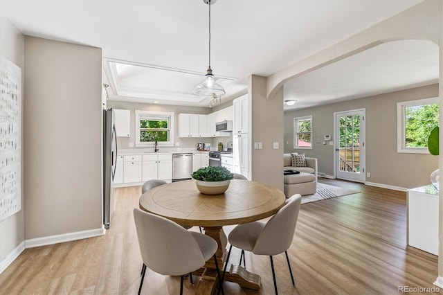 1895 S Emerson St, Denver, CO 80210 - dining space with a raised ceiling, light wood-style floors, arched walkways, and plenty of natural light