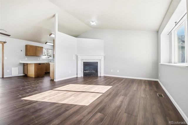 unfurnished living room with dark hardwood / wood-style floors, lofted ceiling, and a premium fireplace