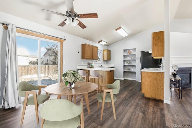 kitchen with ceiling fan, black fridge, dark hardwood / wood-style flooring, kitchen peninsula, and lofted ceiling