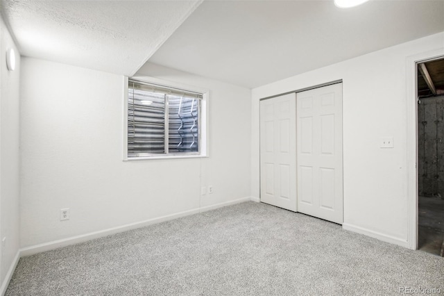 unfurnished bedroom featuring carpet flooring, a textured ceiling, and a closet