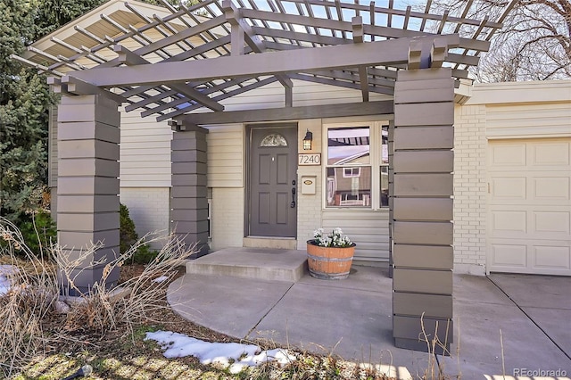 doorway to property with a garage, brick siding, and a pergola