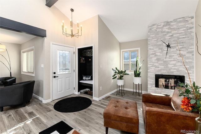 entrance foyer with a tiled fireplace, high vaulted ceiling, hardwood / wood-style flooring, and an inviting chandelier