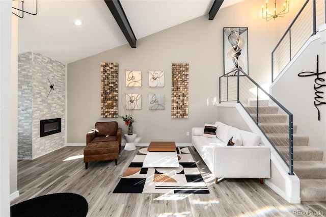 living room with a notable chandelier, beam ceiling, a large fireplace, and hardwood / wood-style flooring