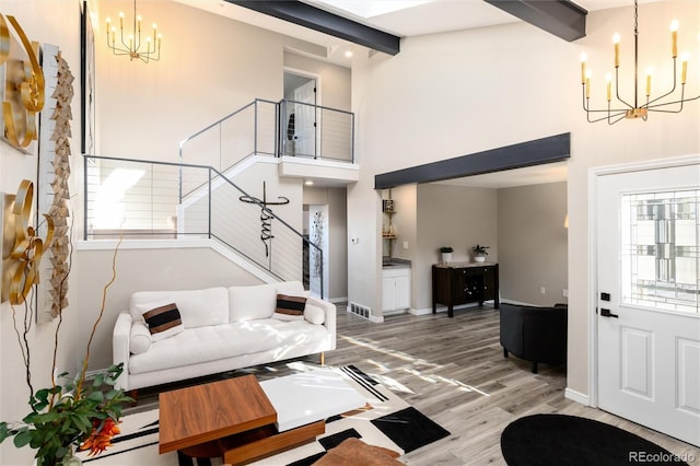 living room featuring an inviting chandelier, hardwood / wood-style flooring, plenty of natural light, and a high ceiling