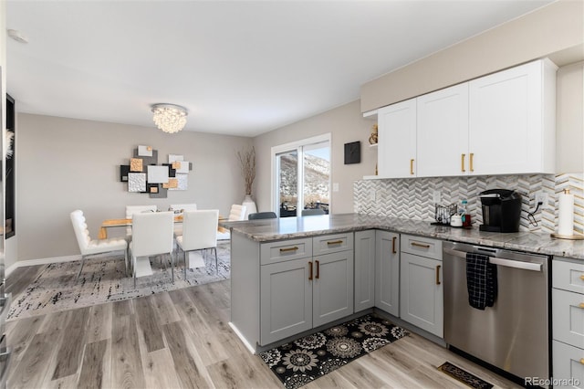 kitchen with white cabinetry, light hardwood / wood-style flooring, dishwasher, kitchen peninsula, and light stone countertops