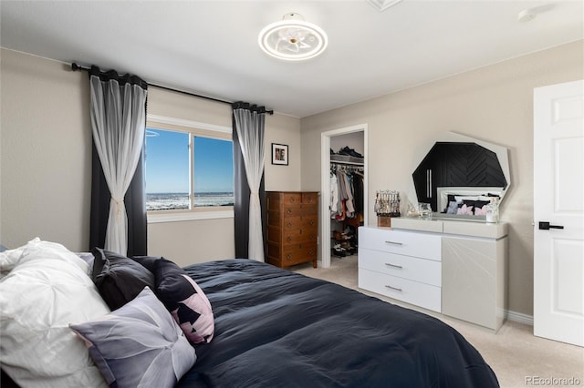 bedroom featuring light carpet, a walk in closet, and a closet