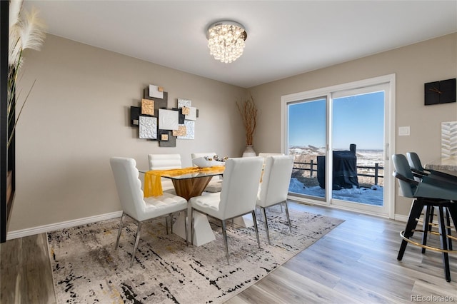 dining area with light wood-type flooring and an inviting chandelier