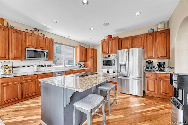kitchen featuring stainless steel appliances, brown cabinetry, and light wood-type flooring