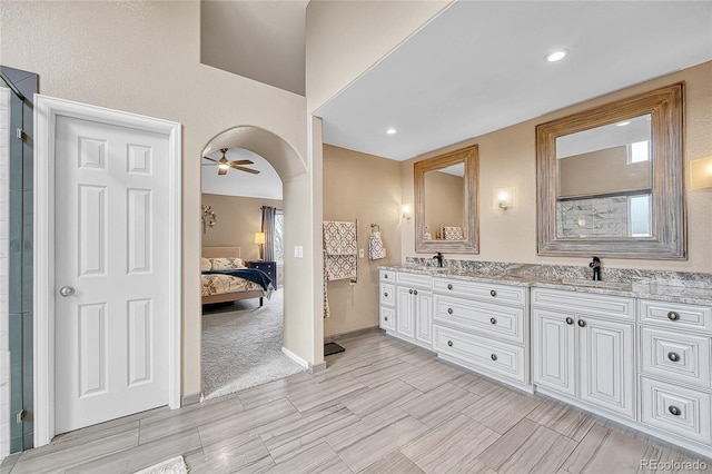ensuite bathroom with ceiling fan, a sink, double vanity, baseboards, and ensuite bathroom