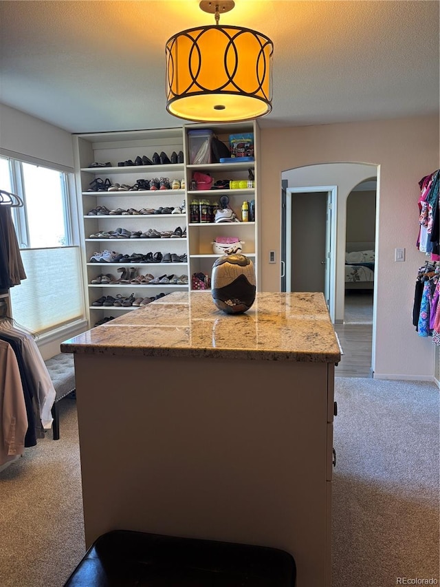 spacious closet featuring light colored carpet and arched walkways