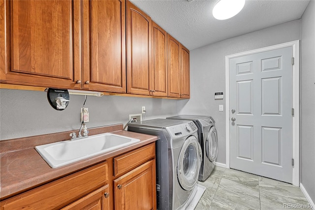 laundry room featuring baseboards, washer and clothes dryer, a textured ceiling, a sink, and cabinet space