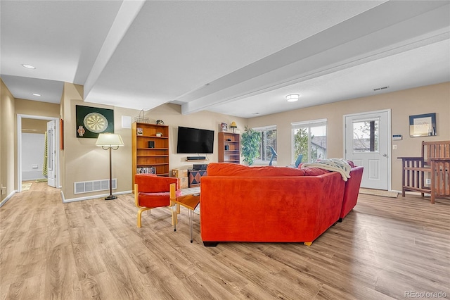 living area featuring baseboards, beamed ceiling, visible vents, and light wood-type flooring
