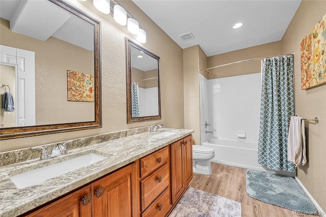 full bathroom featuring a sink, shower / bath combo, double vanity, wood finished floors, and visible vents