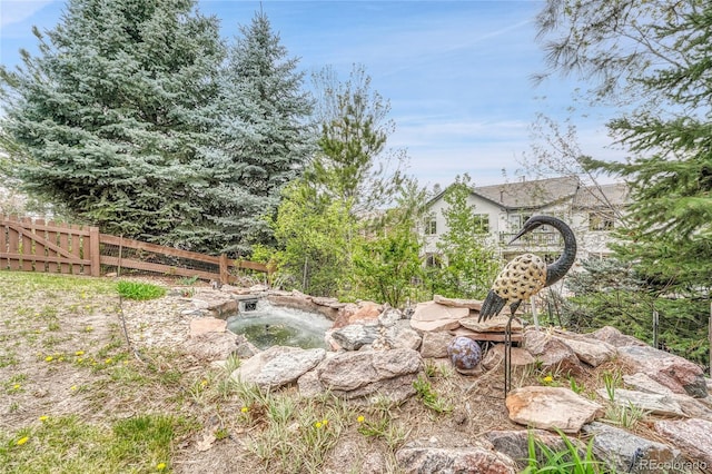view of yard featuring a small pond and fence