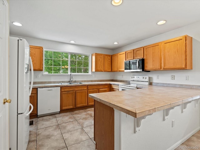386 Monte Vista St, Brighton, CO 80601 - kitchen featuring white appliances, a peninsula, a breakfast bar area, recessed lighting, and tile countertops