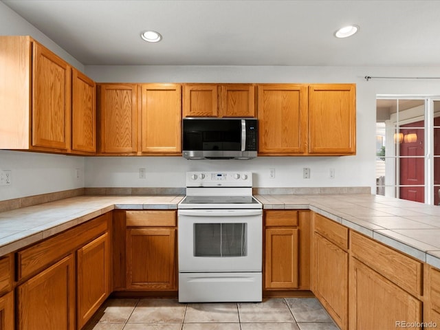 386 Monte Vista St, Brighton, CO 80601 - kitchen featuring stainless steel microwave, electric stove, light tile patterned floors, tile countertops, and recessed lighting