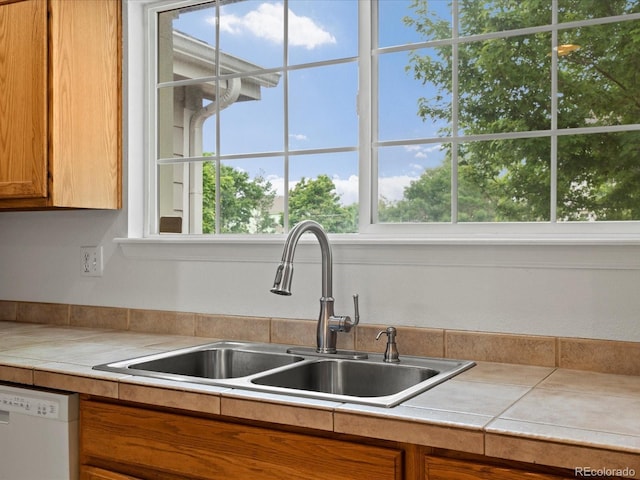 386 Monte Vista St, Brighton, CO 80601 - kitchen featuring dishwasher, brown cabinetry, plenty of natural light, and light countertops