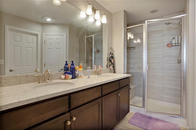 full bathroom with double vanity, a stall shower, and a sink