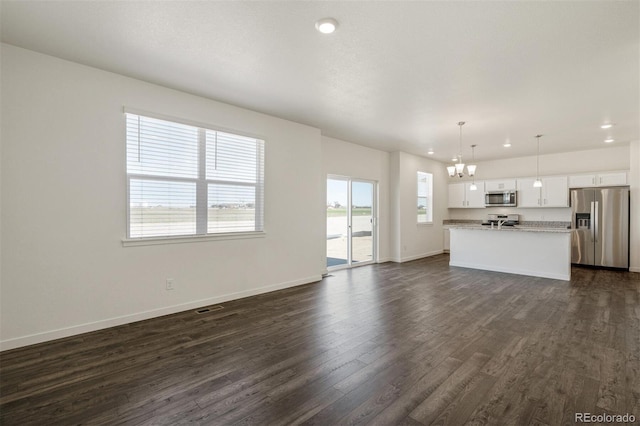 unfurnished living room featuring a notable chandelier and dark hardwood / wood-style flooring