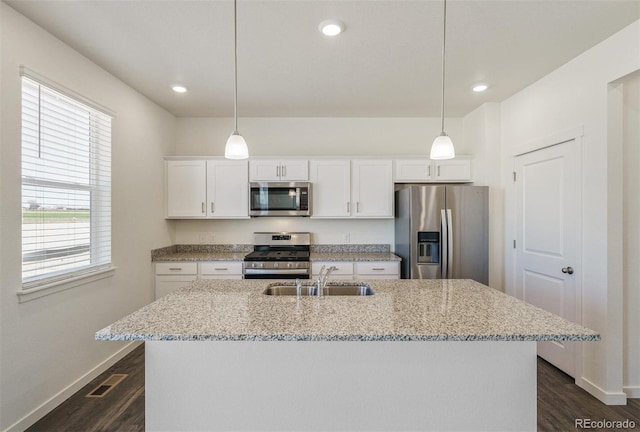 kitchen featuring stainless steel appliances, a kitchen island with sink, sink, white cabinets, and hanging light fixtures