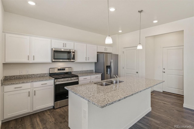 kitchen with stainless steel appliances, a kitchen island with sink, sink, pendant lighting, and white cabinetry