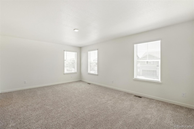 carpeted spare room featuring plenty of natural light