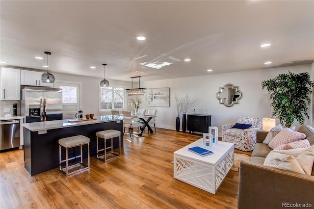 living area featuring light wood-style floors, baseboards, and recessed lighting