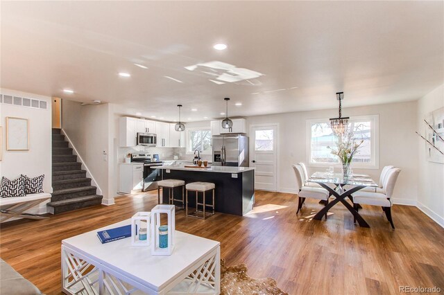 living area featuring recessed lighting, a healthy amount of sunlight, stairway, and wood finished floors