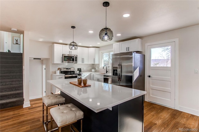 kitchen featuring dark wood-type flooring, white cabinetry, light countertops, appliances with stainless steel finishes, and decorative backsplash