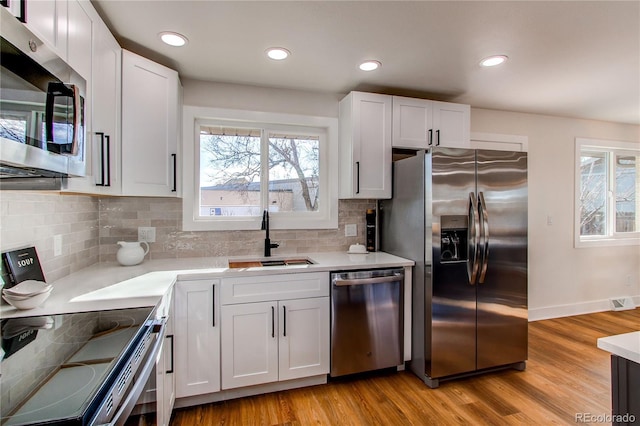 kitchen featuring a sink, white cabinets, light wood-style floors, light countertops, and appliances with stainless steel finishes