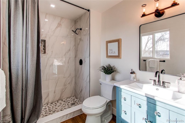 bathroom featuring tiled shower, vanity, toilet, and wood finished floors