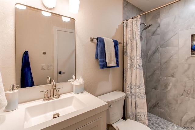 bathroom featuring tiled shower, vanity, and toilet