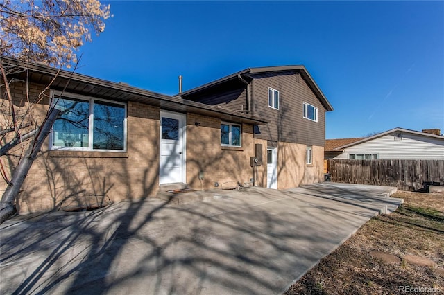 back of property with a patio area, fence, and brick siding