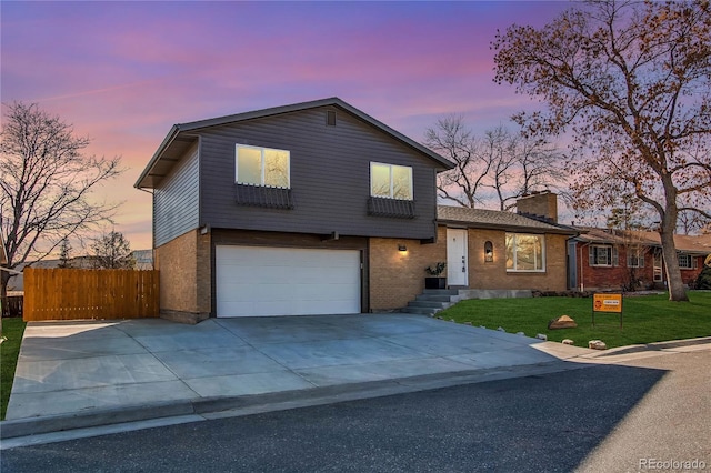 split level home with brick siding, fence, a chimney, and a front lawn