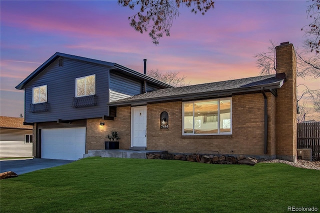 tri-level home featuring brick siding, fence, and a lawn