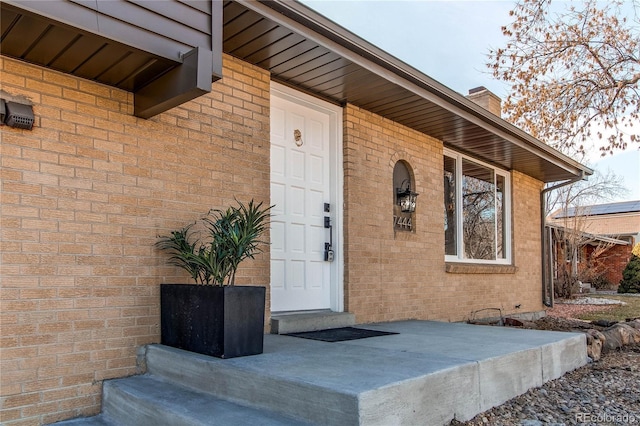 property entrance with brick siding and a chimney